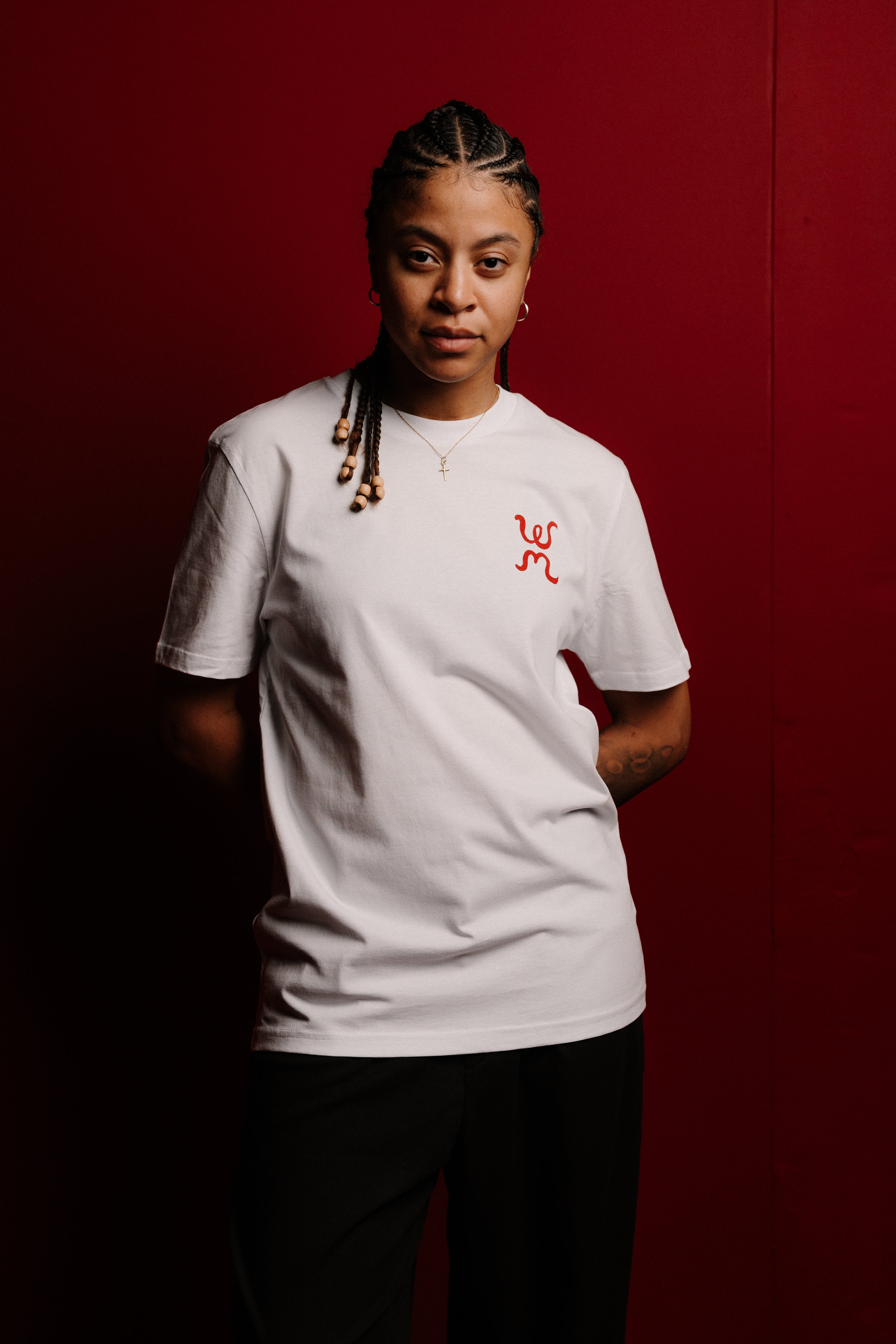 Person wearing a white t-shirt with a red logo against a red background
